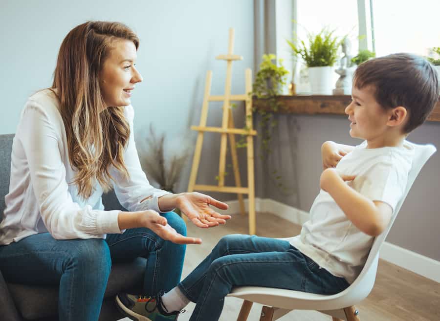 A cheerful young boy talks with a counselor at a health center office.